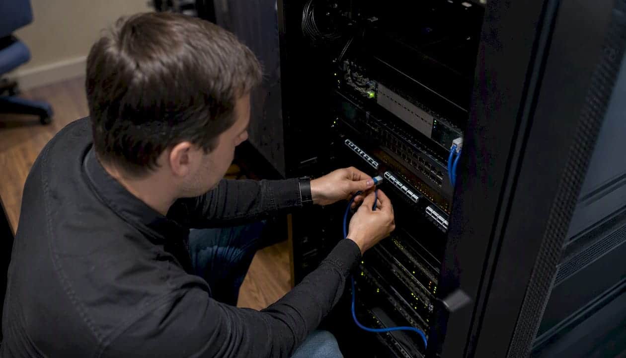 Hands connecting network cable to secure monitoring equipment