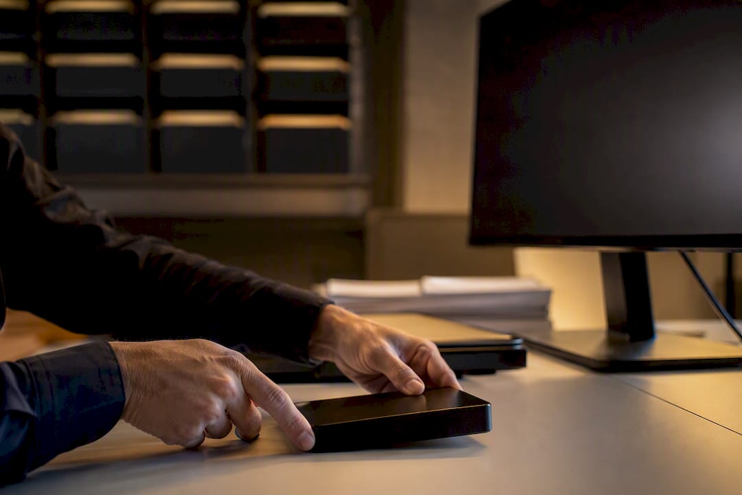 Hands setting hard drive near monitor in records room